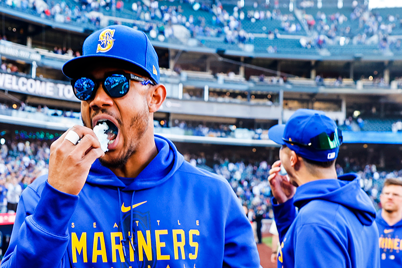 Julio-Rodriguez putting a puff of blue cotton candy into his mouth on the warning track in Seattle after a win.