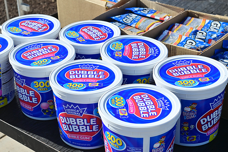 A spring training photo. Nine large pails of Dubble Bubble are neatly laid out, and behind them, two large boxes of sunflower seeds.