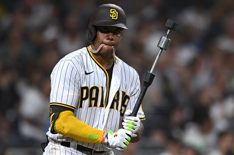 Juan-Soto back in his Padres days, standing in the on-deck circle with his chain in his mouth for some reason, holding a weird metal bat thingie that honestly looks like it would be really good for killing zombies.