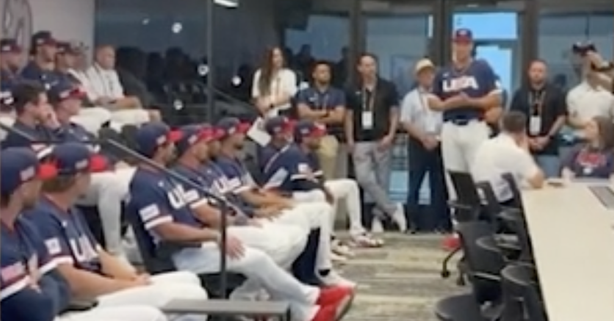A conference room in the greater Pheonix area. Team USA, in full uniform, sits reclined in two rows of seats stretching away from the camera on the left. On the right, in front of a glass wall so that everybody has to squint at him, stands Aaron Judge, hands clasped, giving the speech of his life.