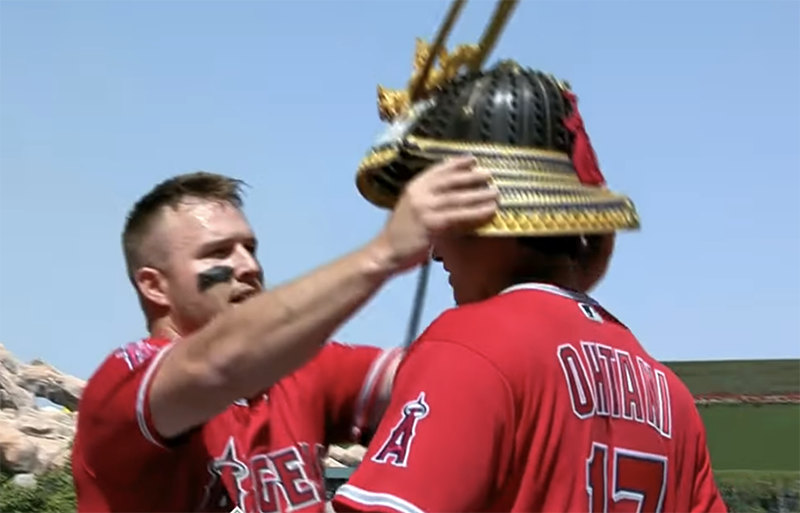 Trout places a Kabuto samurai hat on Ohtani's head after a home run.